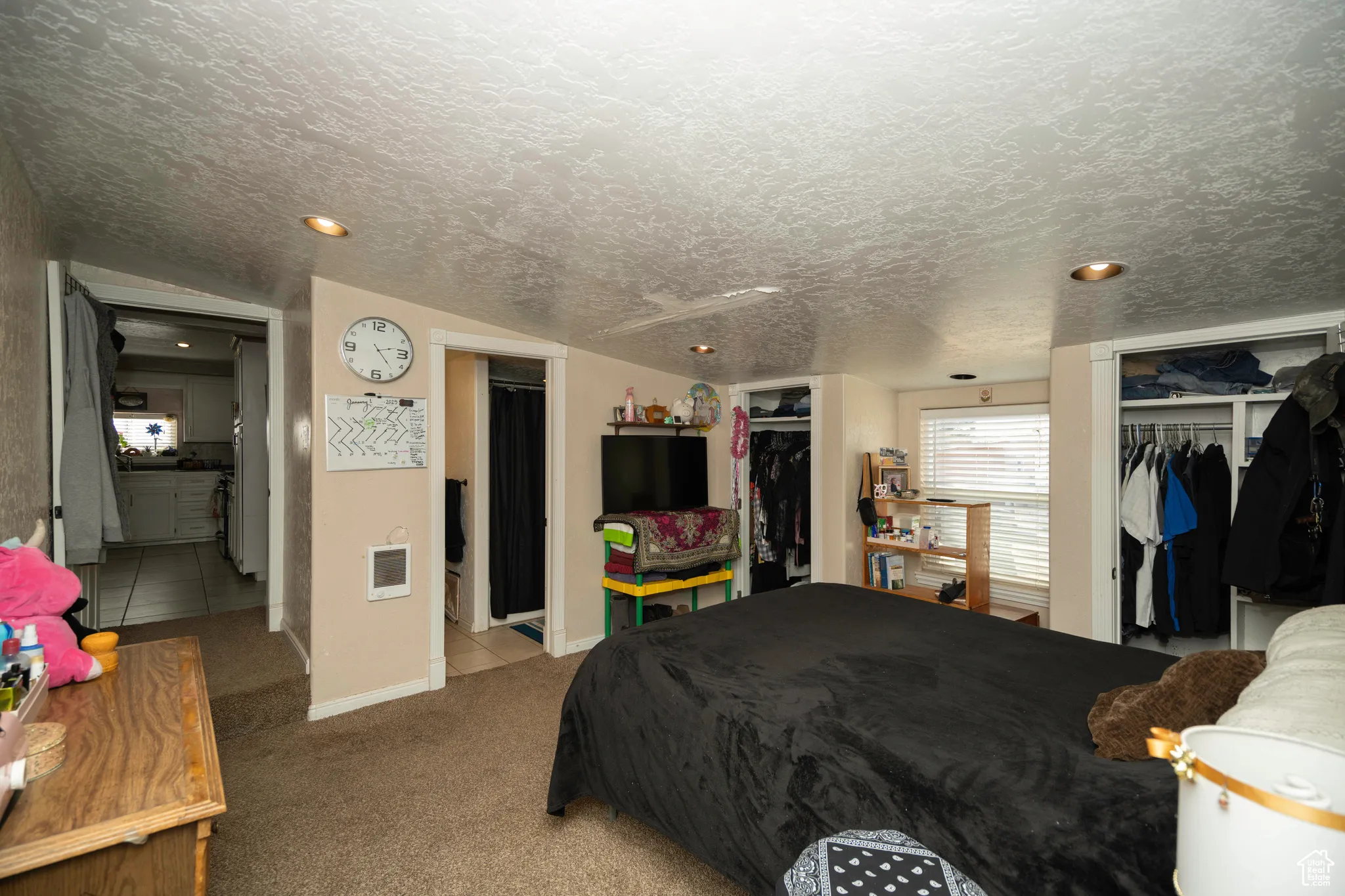 Bedroom with light colored carpet and a textured ceiling