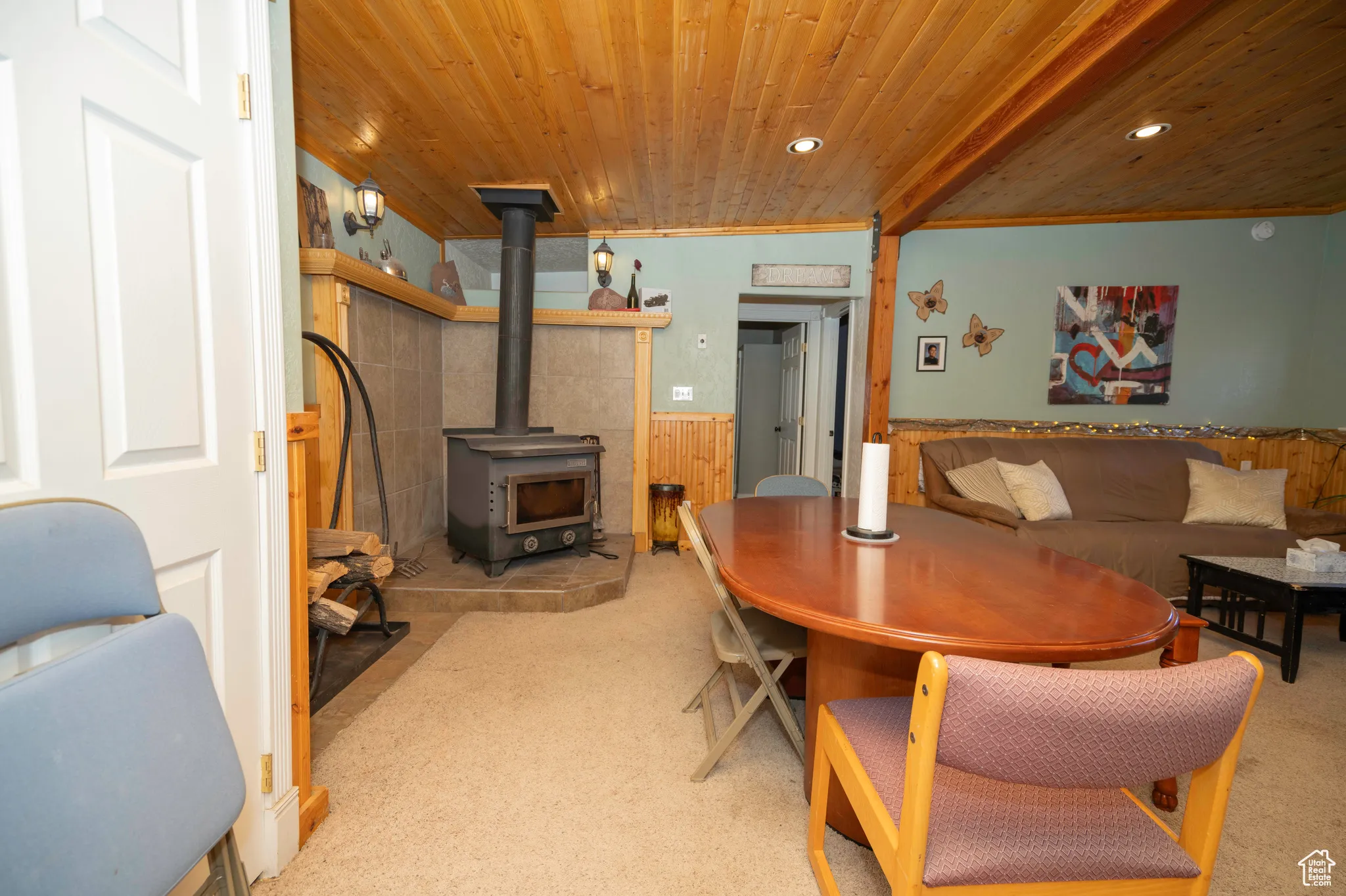 Dining space with crown molding, wood ceiling, light colored carpet, and a wood stove