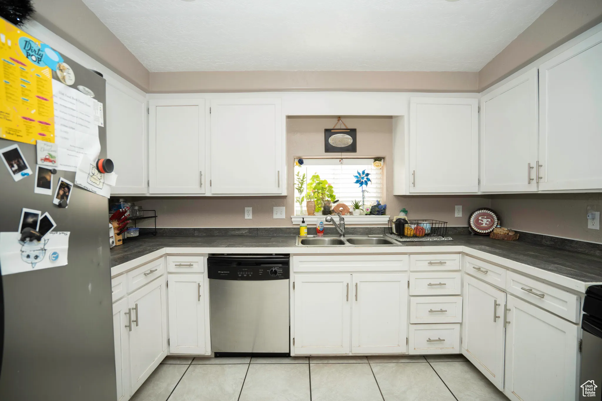 Kitchen featuring sink, light tile patterned floors, white cabinets, and appliances with stainless steel finishes