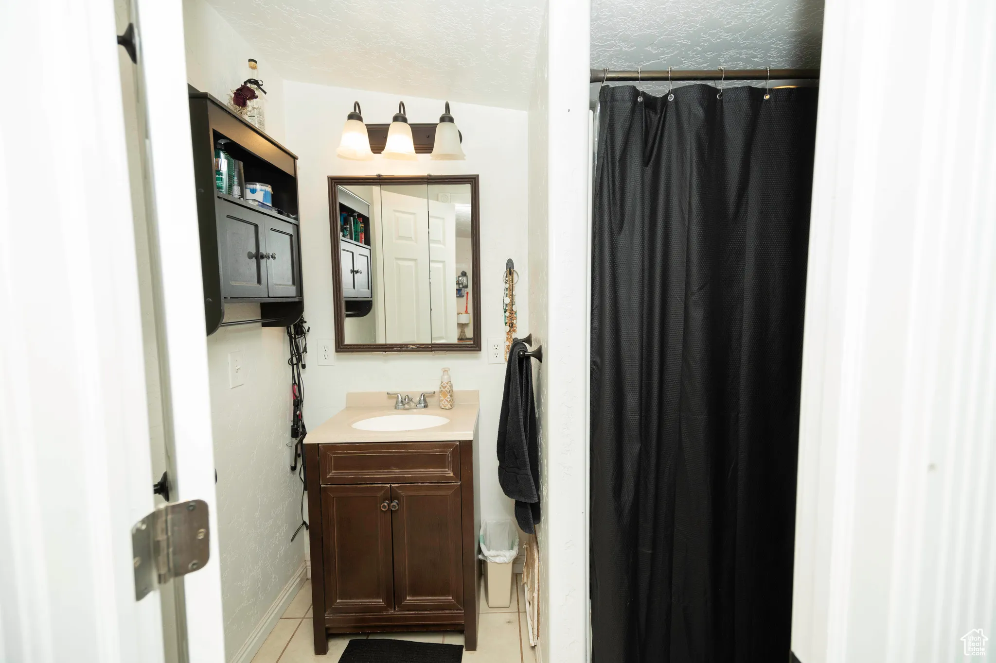 Bathroom with tile patterned floors, vanity, curtained shower, and a textured ceiling
