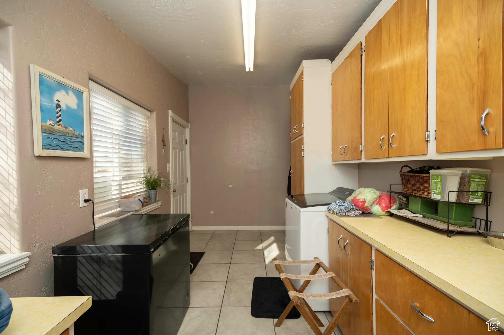 Washroom featuring light tile patterned floors, washer / clothes dryer, and cabinets