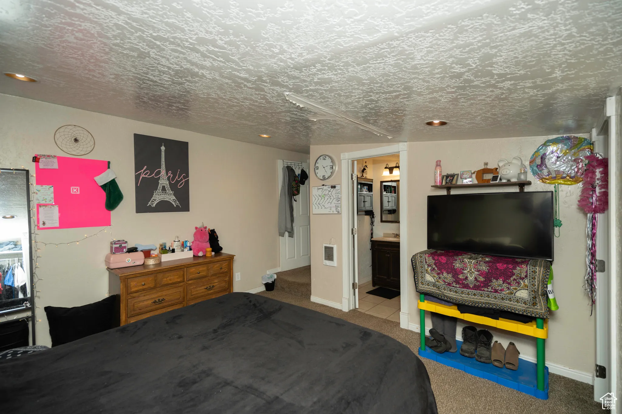 Carpeted bedroom with ensuite bath and a textured ceiling
