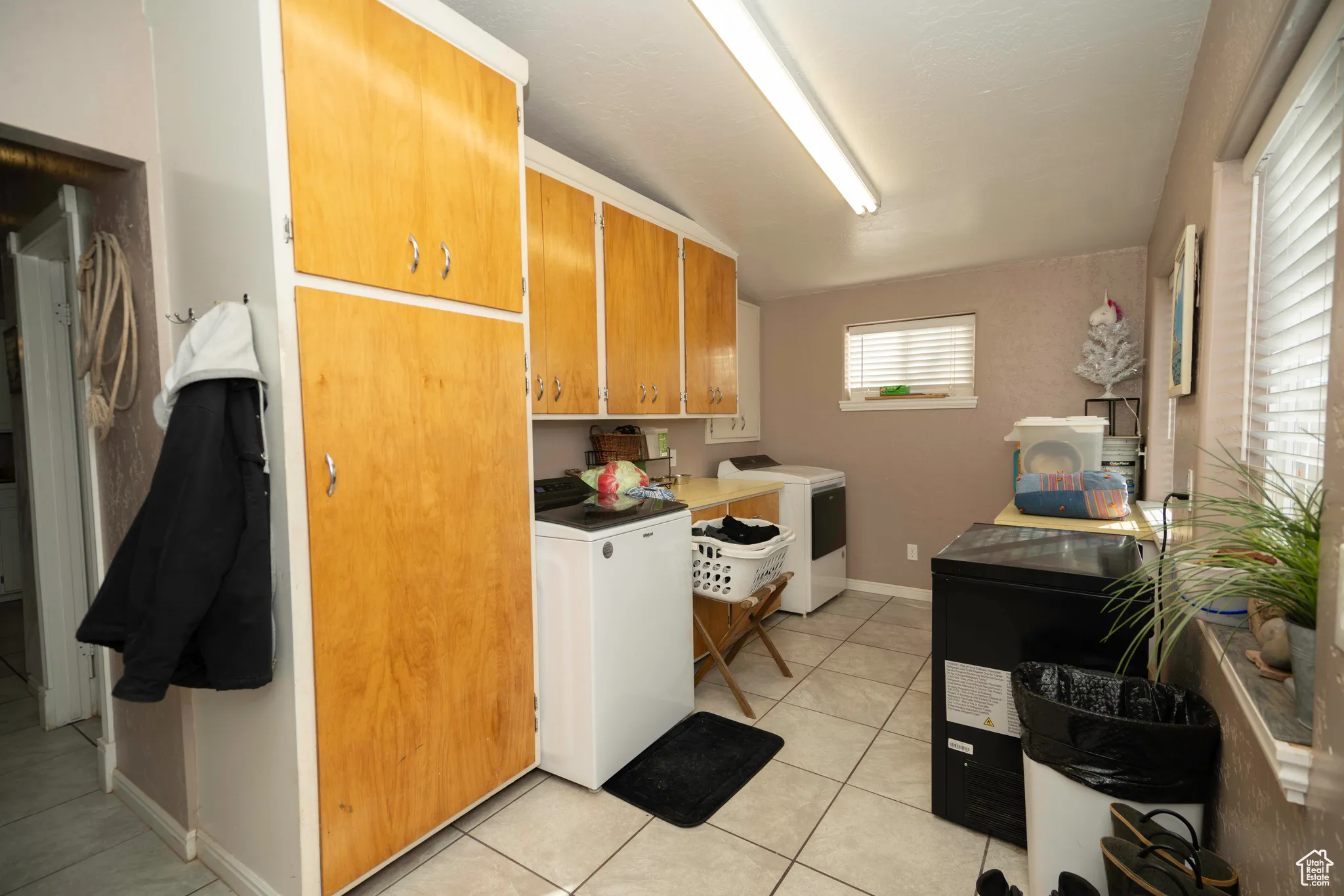 Laundry area featuring cabinets, washing machine and dryer, and light tile patterned floors
