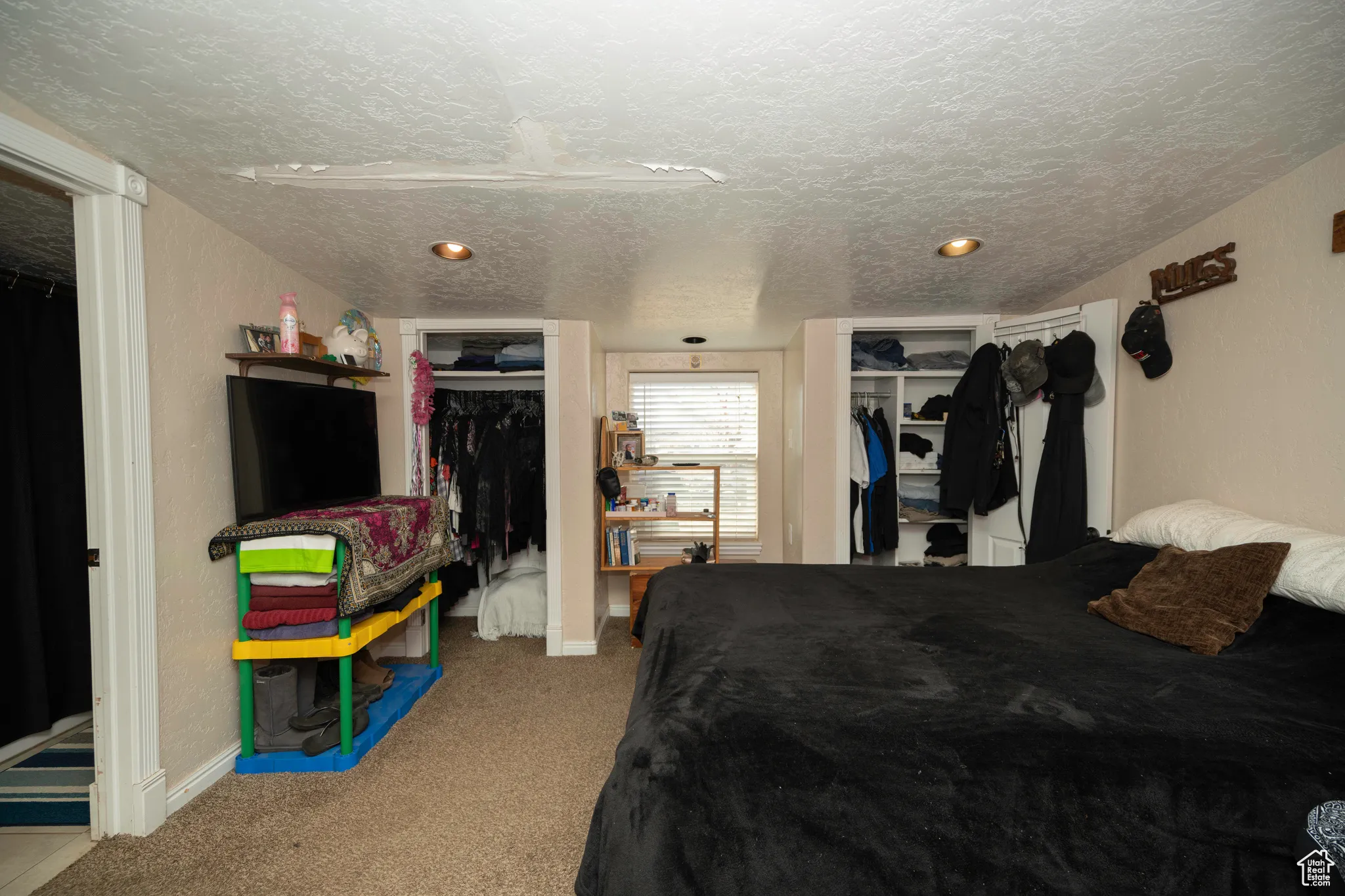 Bedroom featuring multiple closets, carpet flooring, and a textured ceiling