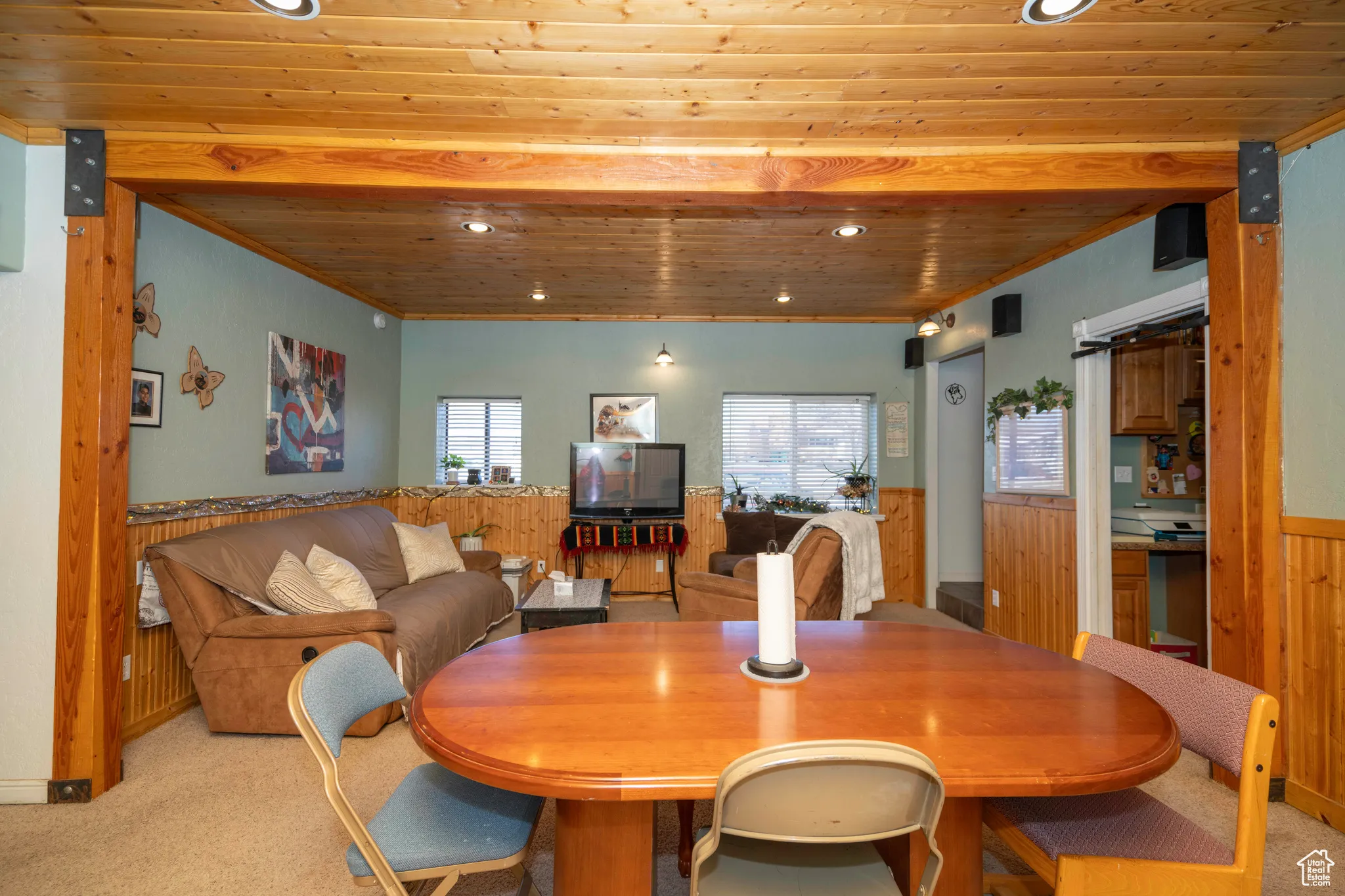 Dining room featuring wood ceiling, wooden walls, light carpet, and a wealth of natural light