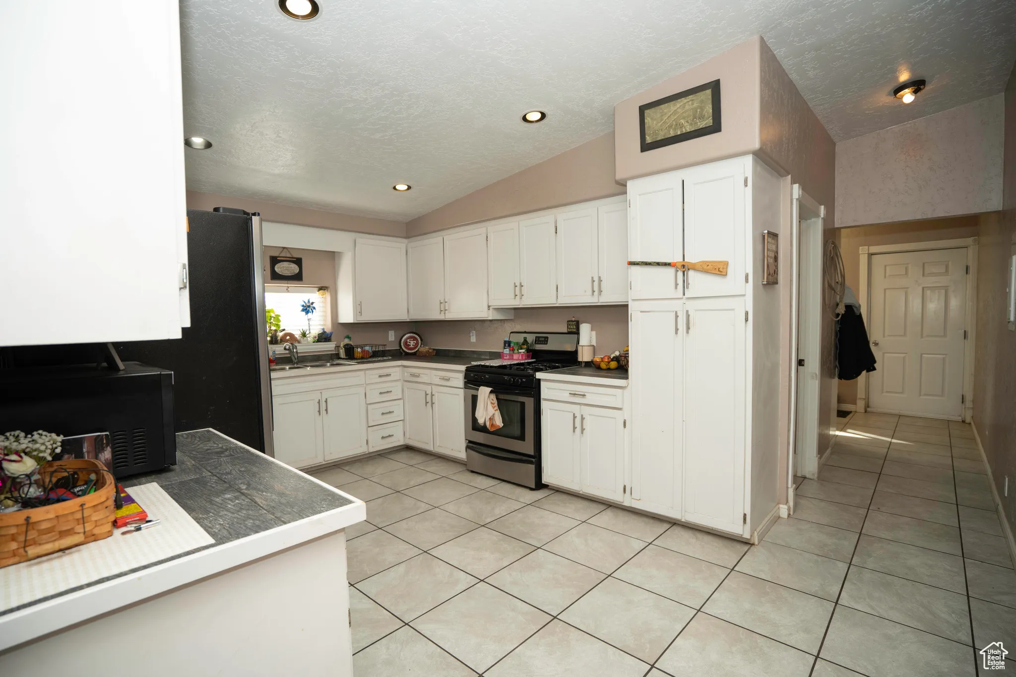 Kitchen featuring white cabinetry, stainless steel range with gas cooktop, sink, and vaulted ceiling