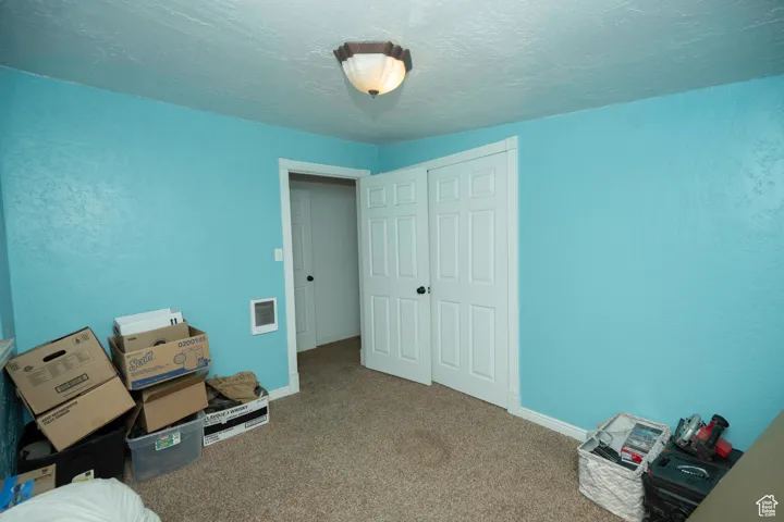 Unfurnished bedroom with a closet, a textured ceiling, and carpet