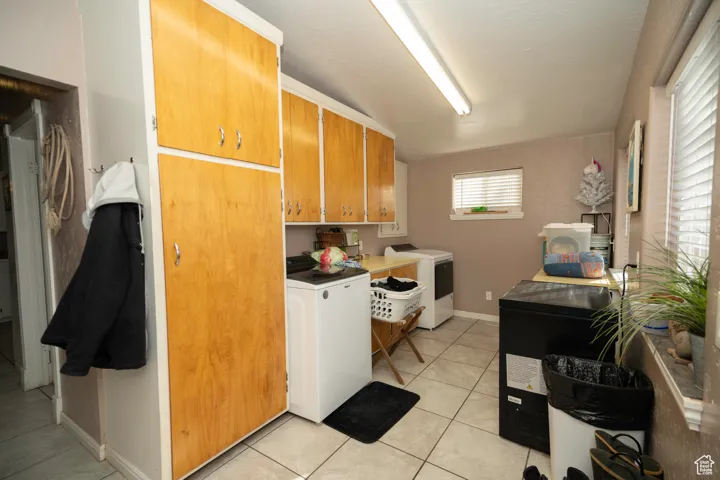 Laundry area featuring cabinets, washing machine and dryer, and light tile patterned floors