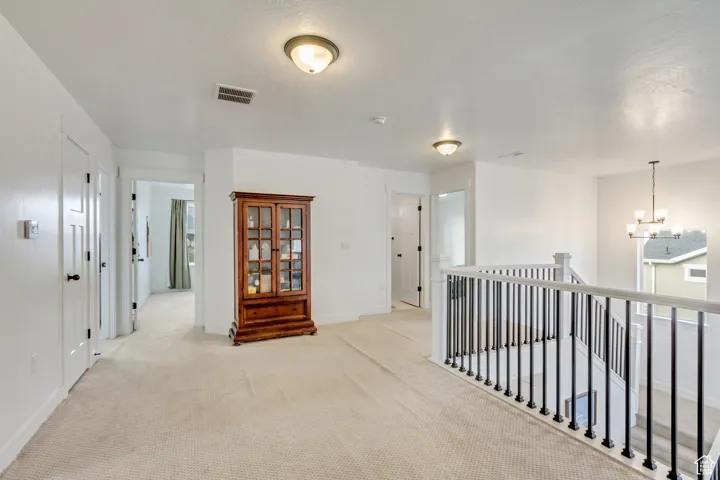 Hall with a notable chandelier and light colored carpet