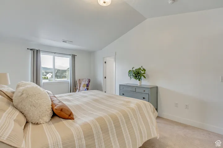 Bedroom featuring vaulted ceiling and light colored carpet