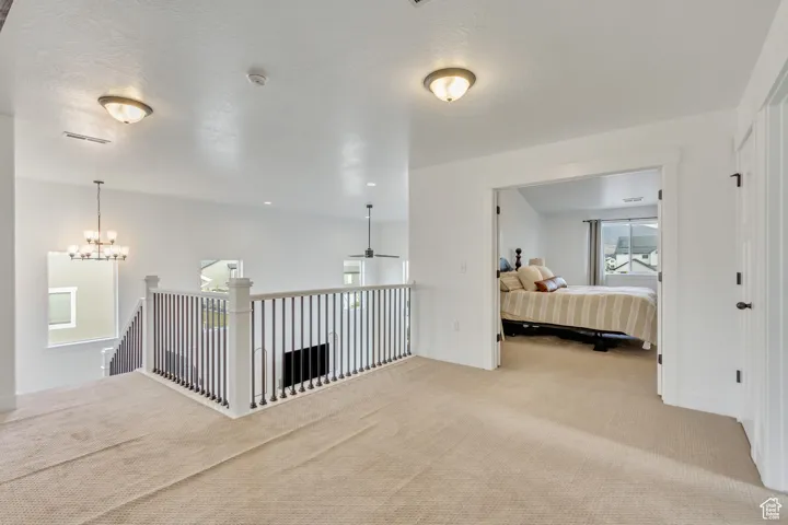 Hall with a chandelier, carpet flooring, and a textured ceiling