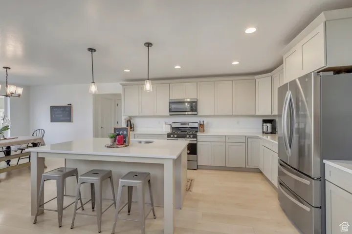 Kitchen with sink, stainless steel appliances, decorative light fixtures, and a kitchen island