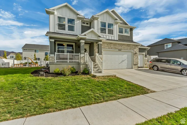 View of front of property featuring a porch, a front yard, and a garage