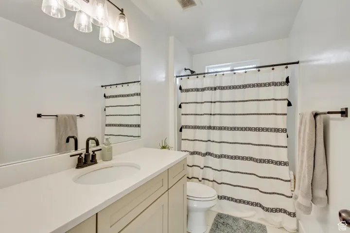 Bathroom with vanity, curtained shower, toilet, and tile patterned floors