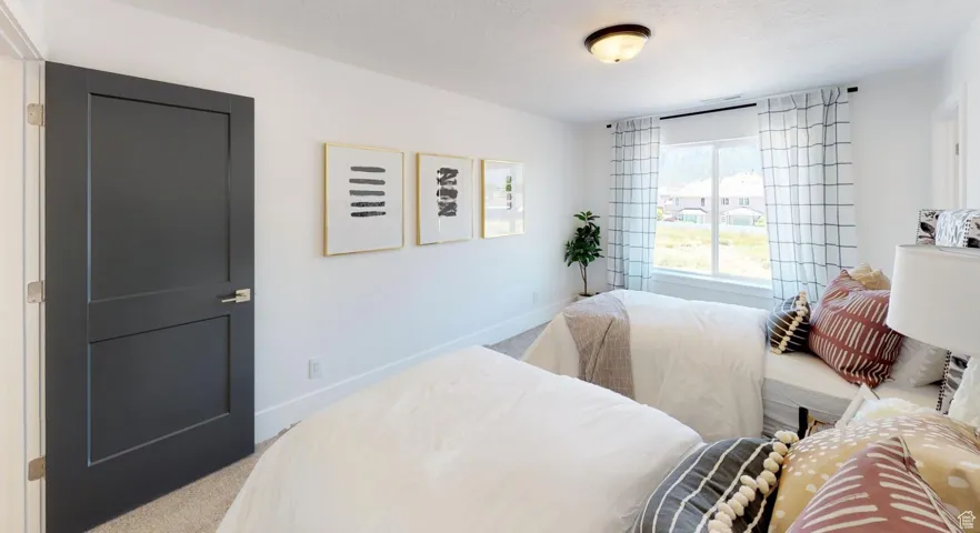 Bedroom with light colored carpet and a textured ceiling