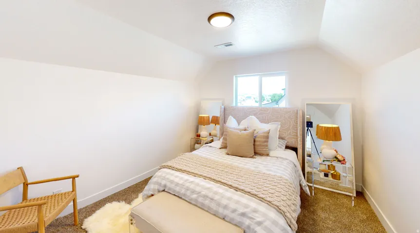 Bedroom featuring carpet, lofted ceiling, and a textured ceiling