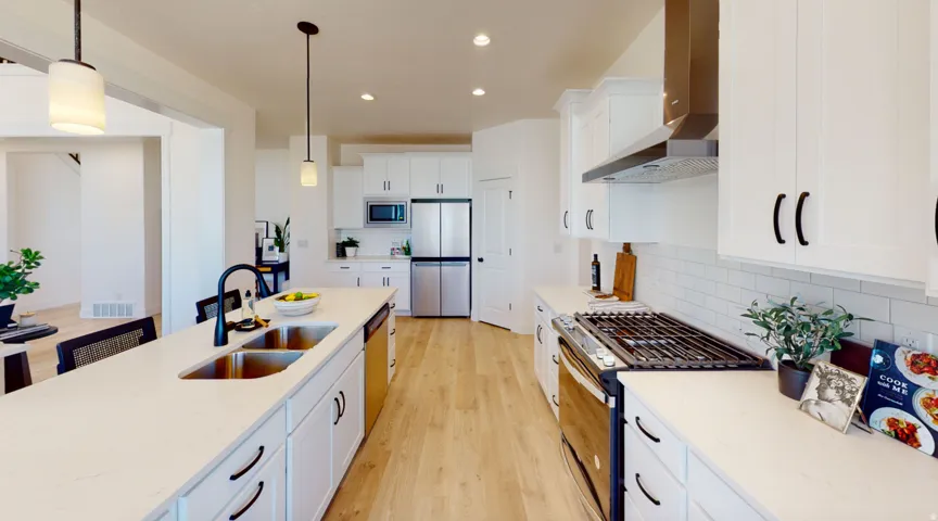 Kitchen featuring stainless steel appliances, white cabinetry, light wood finished floors, wall chimney range hood, and light stone counters