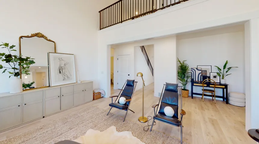 Sitting room featuring light wood-type flooring and a towering ceiling