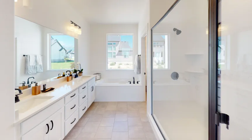 Full bathroom with double vanity, a shower stall, light tile patterned floors, and a garden tub