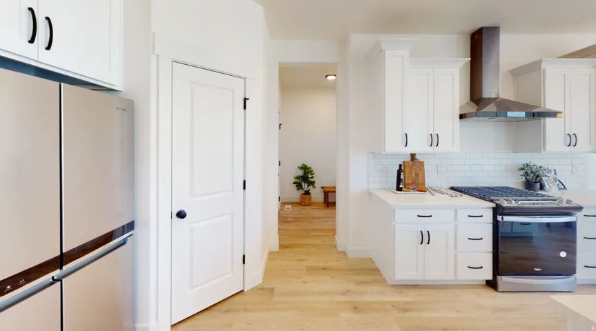 Kitchen with white cabinetry, gas stove, and wall chimney exhaust hood