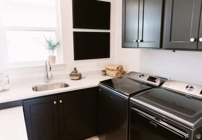 Laundry room with cabinets, separate washer and dryer, and sink