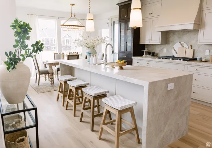 Kitchen with premium range hood, a kitchen island with sink, and a breakfast bar