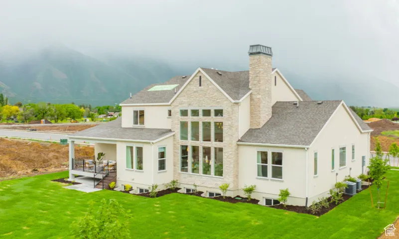Rear view of property featuring cooling unit, a mountain view, and a lawn