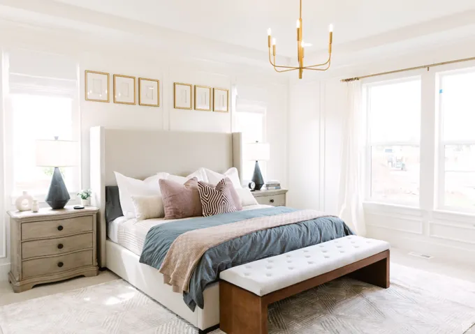 Bedroom with light colored carpet, multiple windows, and a notable chandelier