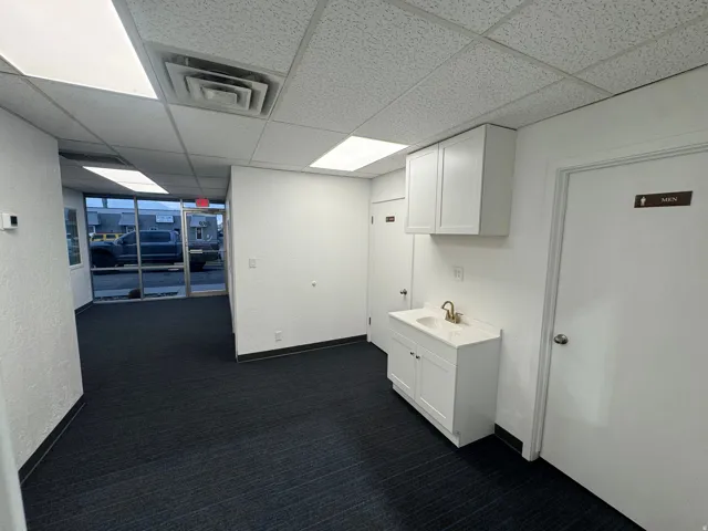 Corridor with a drop ceiling, dark carpet, and a textured wall