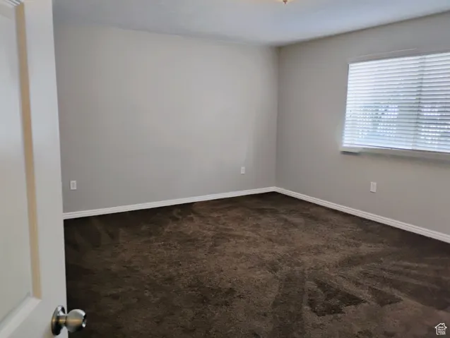 Empty room with baseboards and dark carpet