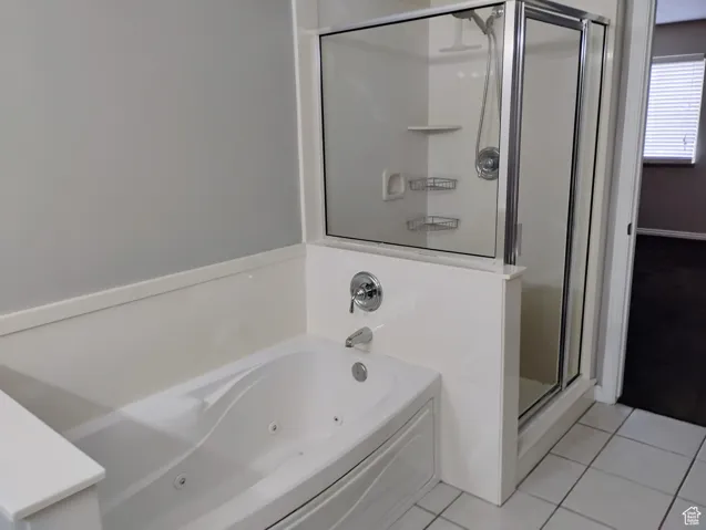 Bathroom with a tub with jets, tile patterned floors, and a shower stall