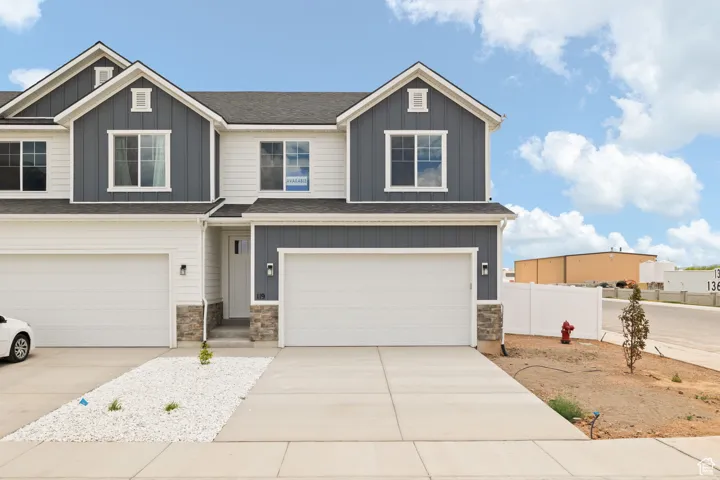 Craftsman house with board and batten siding, an attached garage, stone siding, and concrete driveway