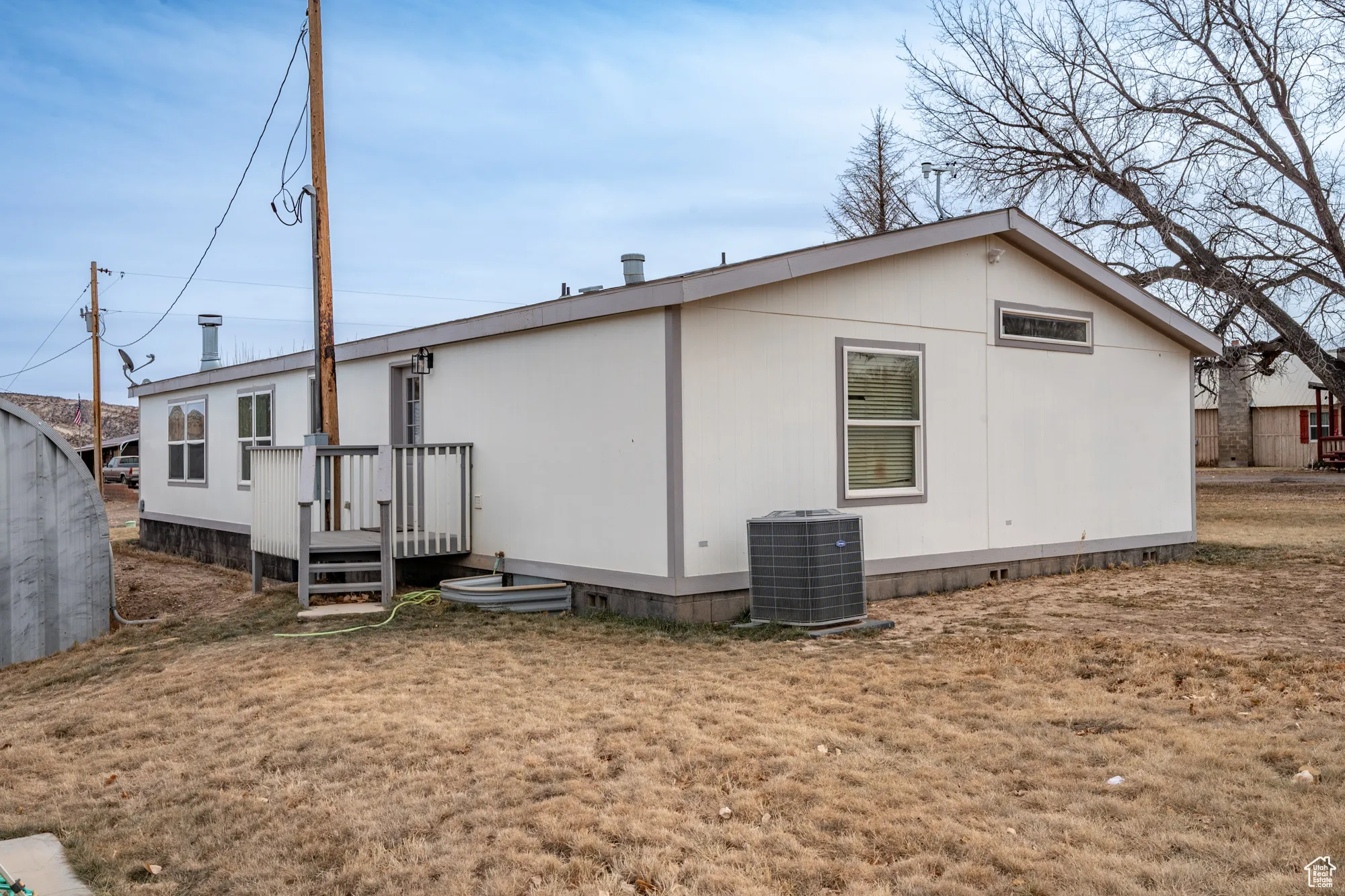 View of side of property featuring central AC unit and a lawn