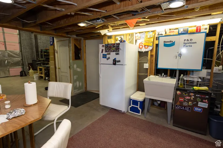 Basement with white refrigerator and sink