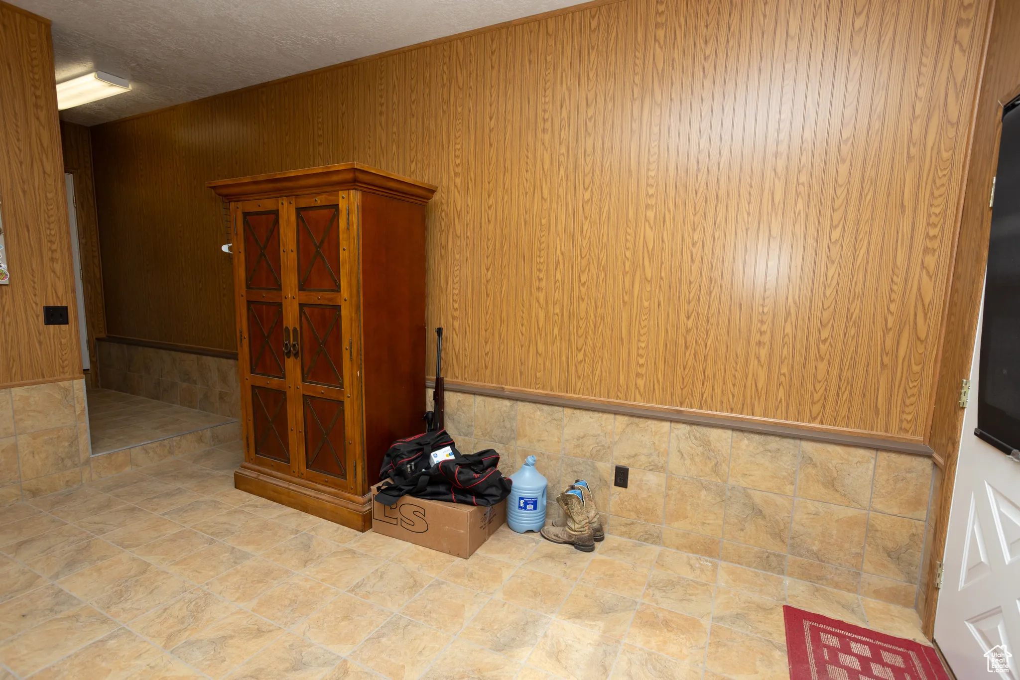 Spare room featuring a textured ceiling and wooden walls