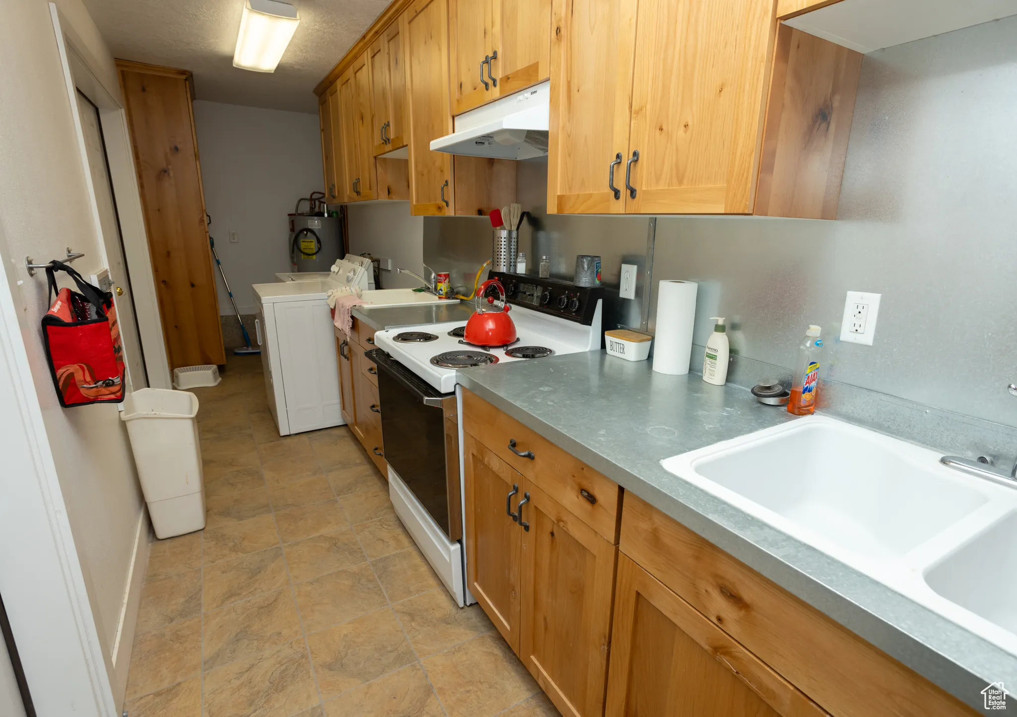 Kitchen with white electric range, sink, and water heater