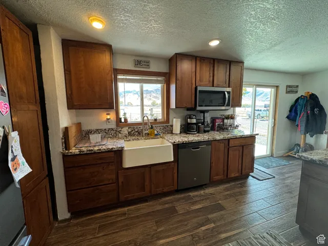 Kitchen with dark wood-type flooring, appliances with stainless steel finishes, sink, and plenty of natural light