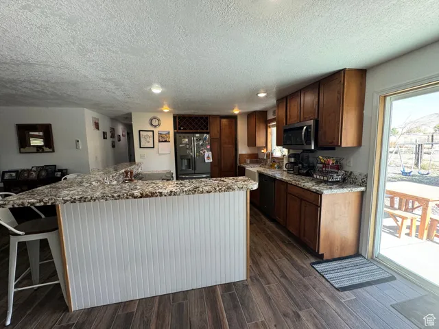 Kitchen with sink, dark wood-type flooring, light stone countertops, and appliances with stainless steel finishes
