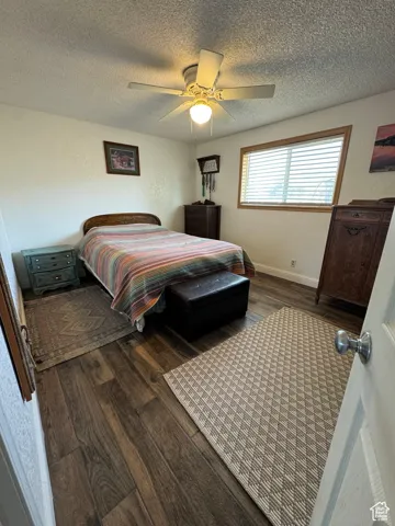 Bedroom with ceiling fan, dark hardwood / wood-style floors, and a textured ceiling