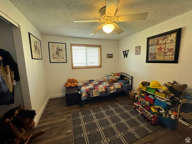 Bedroom with dark wood-type flooring, ceiling fan, and a textured ceiling