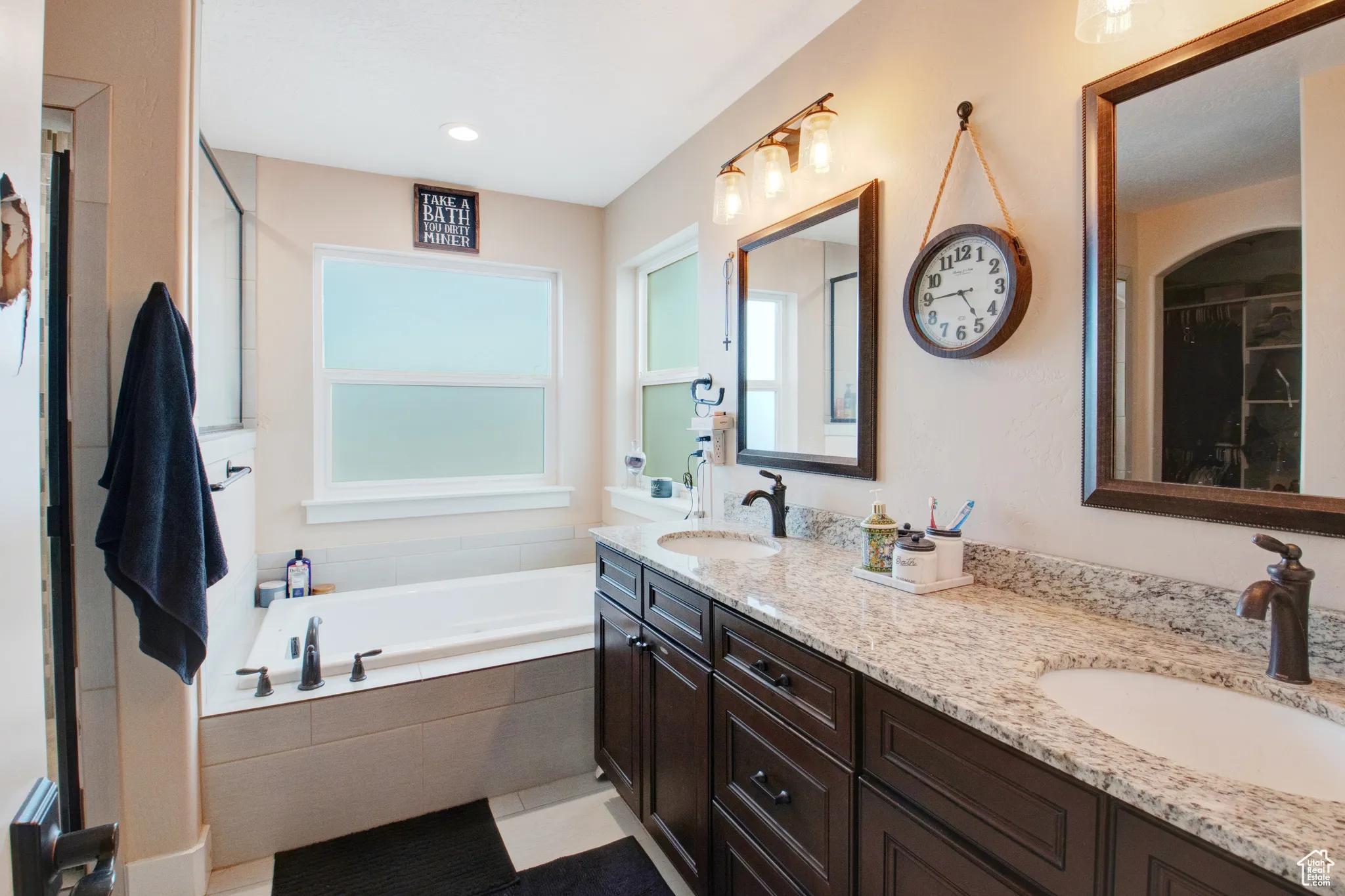 Bathroom featuring vanity, tiled tub, and tile patterned floors