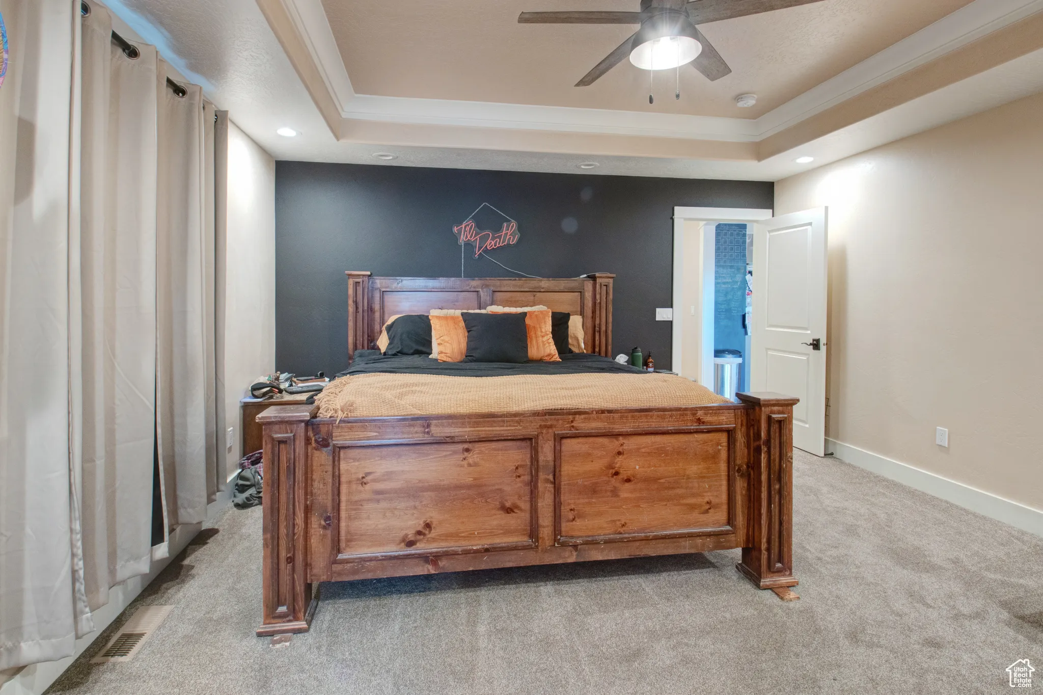 Carpeted bedroom with crown molding, ceiling fan, and a tray ceiling