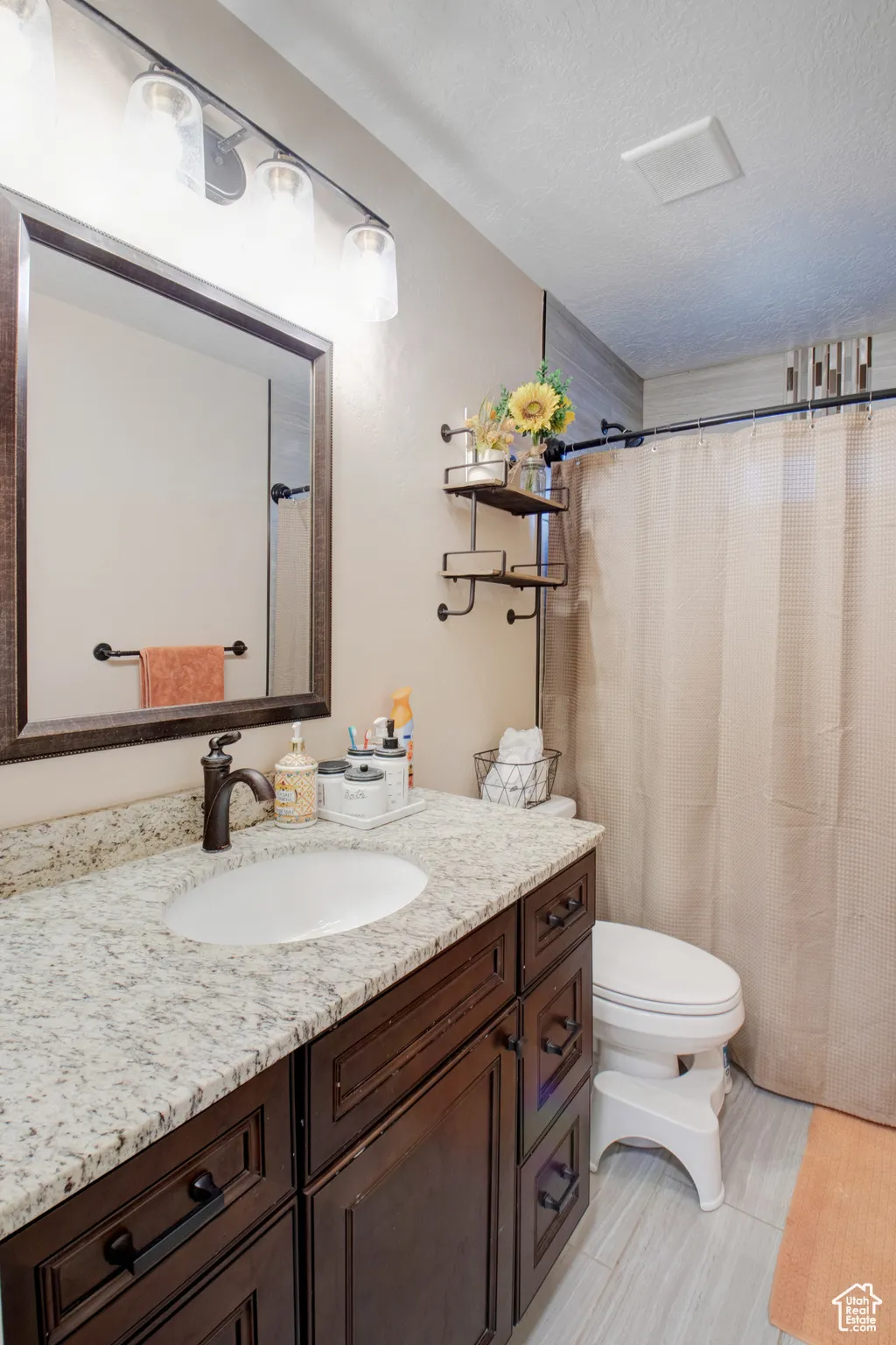 Bathroom with vanity, a textured ceiling, and toilet