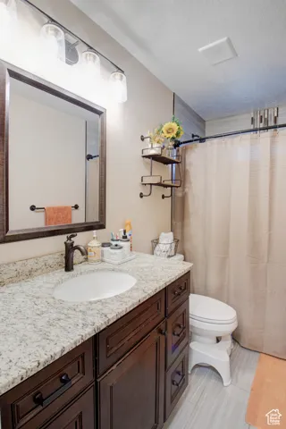 Bathroom with vanity, a textured ceiling, and toilet