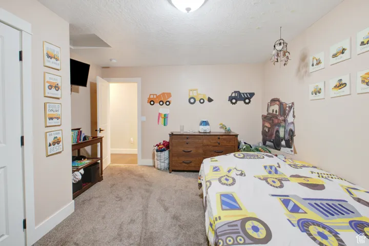 Bedroom with light colored carpet and a textured ceiling
