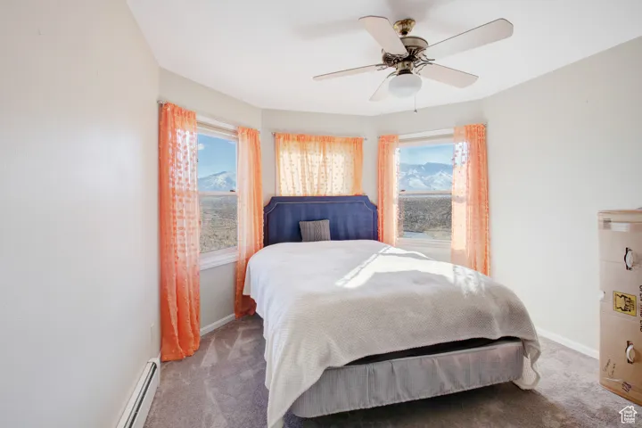 Bedroom with a baseboard heating unit, carpet flooring, and ceiling fan