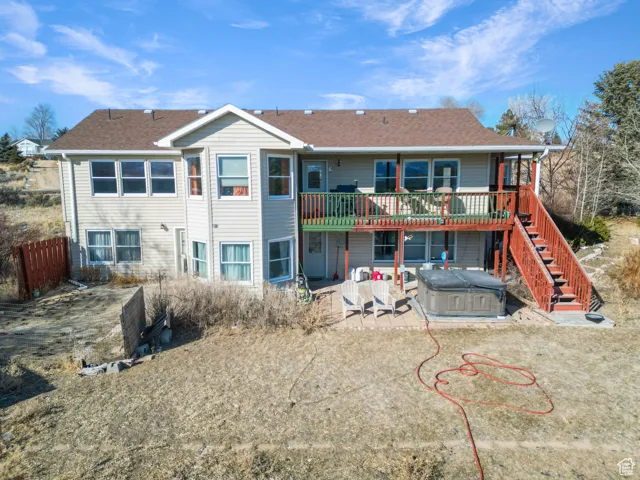 Back of house featuring a hot tub, a patio, and a deck