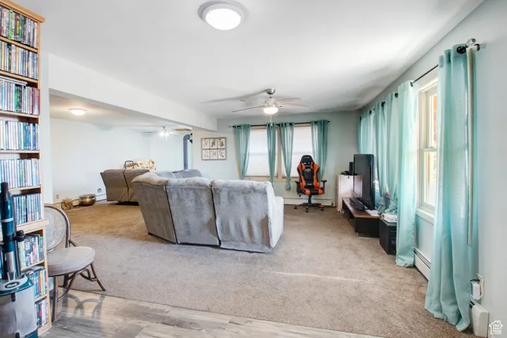 Living room featuring light carpet, ceiling fan, and baseboard heating
