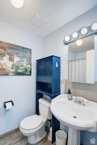 Bathroom featuring tasteful backsplash, sink, hardwood / wood-style flooring, and toilet