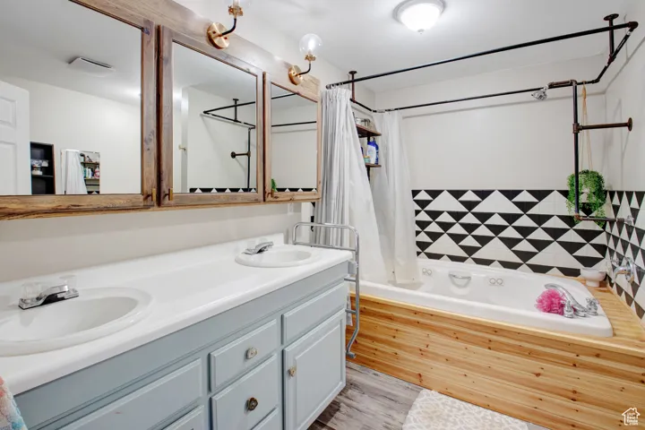 Bathroom featuring vanity, hardwood / wood-style floors, and shower / bath combo with shower curtain